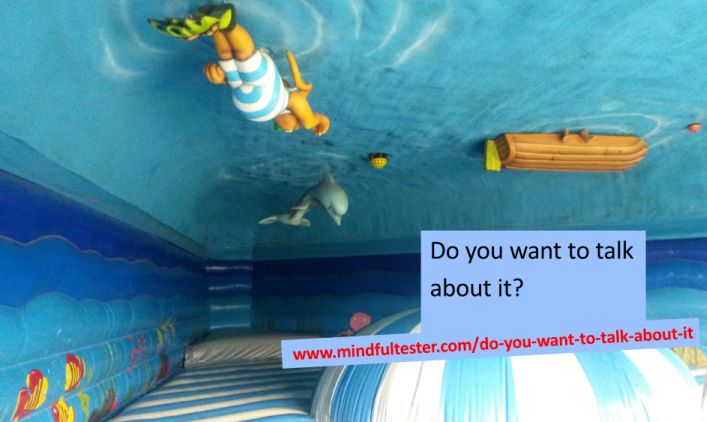 In the ceiling a cartoon figure and a dolphin are swimming. There is also the bottom of a boat. The walls are blue with fishes and the floor contains blue white striped objects. Showing texts “Do you want to talk about it?” and “mindfultester.com/do-you-want-to-talk-about-it”!