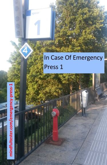 A view of a traing station with a pole with a sign "1". Showing texts “In Case Of Emergency Press 1” and “mindfultester.com/emergency-press-1”!